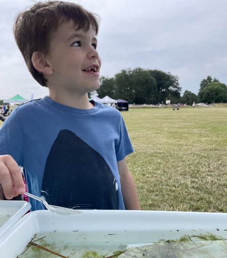 Boy pond dipping with park in the background