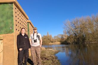 Kathryn Dunnett, Reserves Officer and Dan Townsend, Senior Reserves Officer, standing by the lake and the new Sand Martin Bank at Amwell Nature Reserve 