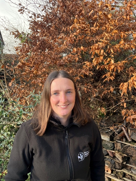 A photo of Kathryn Dunnett, Reserves Officer standing in front of a hedge