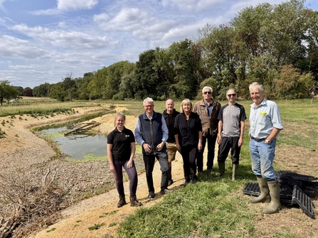 A group of volunteers and the landowner standing for a group photo in front of the new restoration works