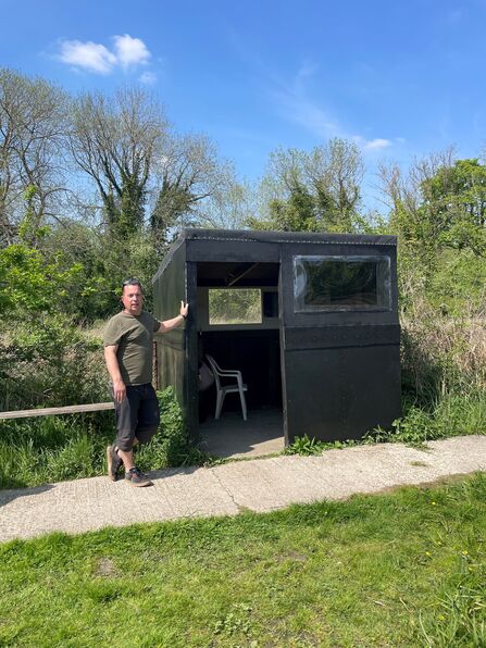 Anthony standing against a hut at Sabey's Pool