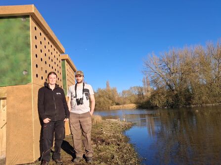 Kathryn Dunnett, Reserves Officer and Dan Townsend, Senior Reserves Officer, standing by the lake and the new Sand Martin Bank at Amwell Nature Reserve 