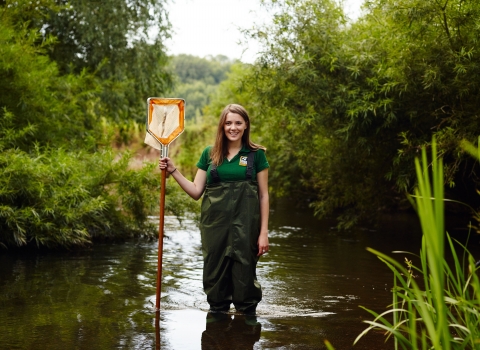 Sophie standing in a river with a net