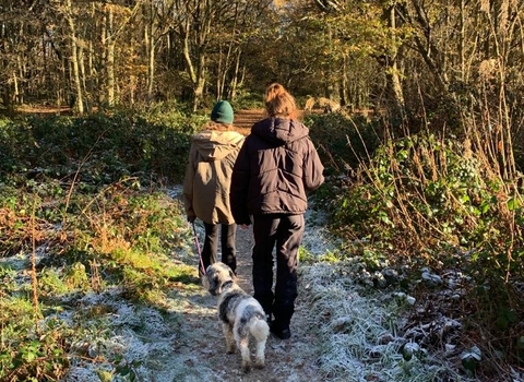 two young girls out walking a dog in the woods in winter